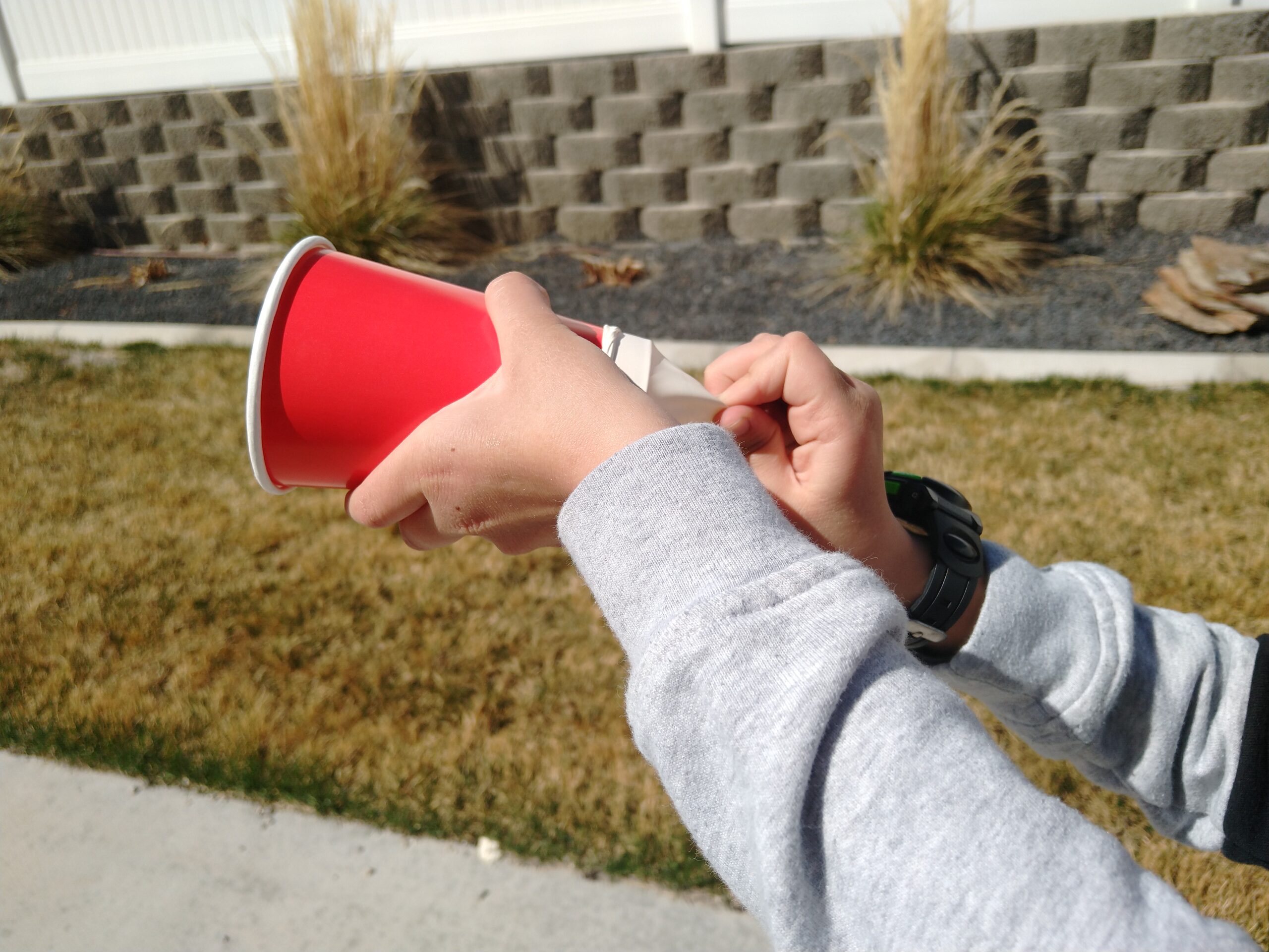 Boy using marshmallow shooter by pulling the balloon back and letteing go.